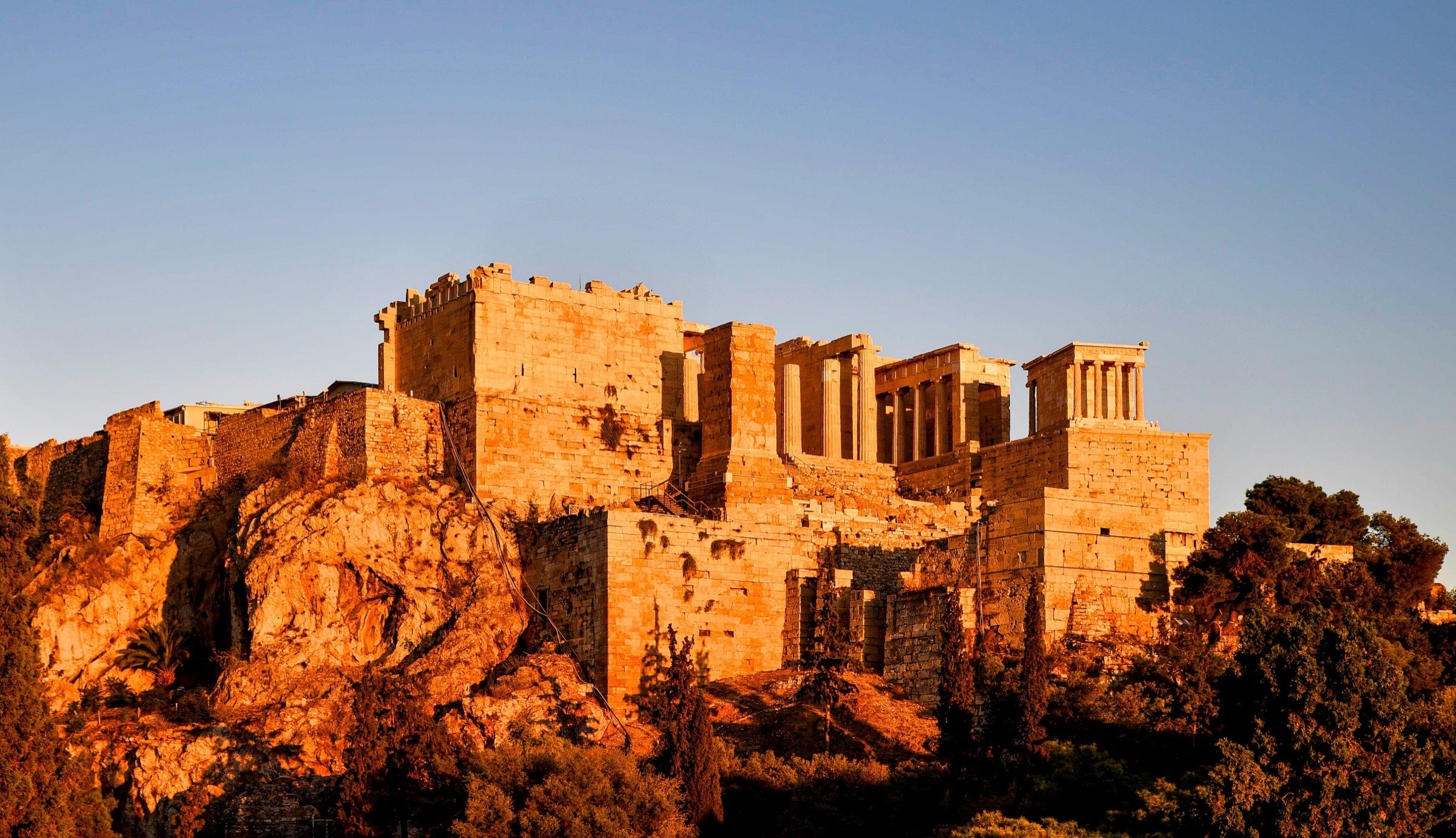 Athens in warm evening gold, the Acropolis rising above the city.